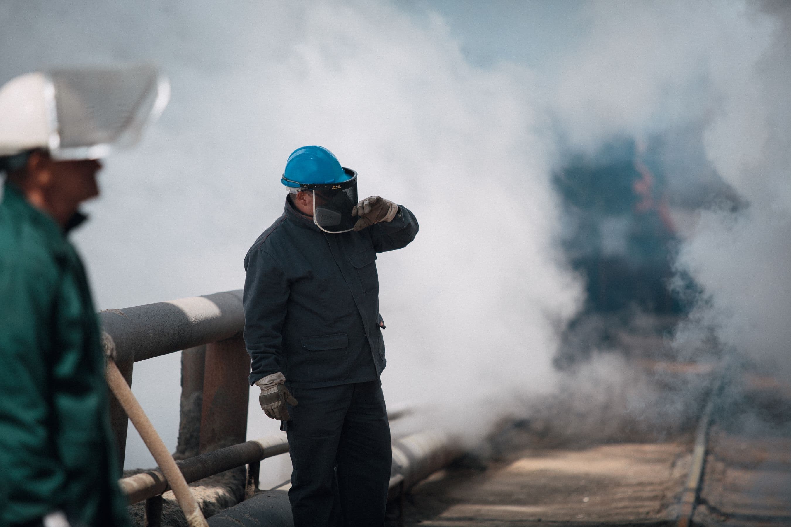 Trabajador industrial con casco y protección facial en planta con vapor
